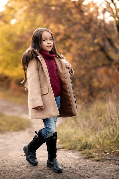 Feliz niña adorable jugando con hojas de otoño caídas