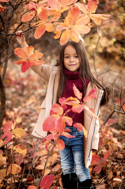 Feliz niña adorable jugando con hojas de otoño