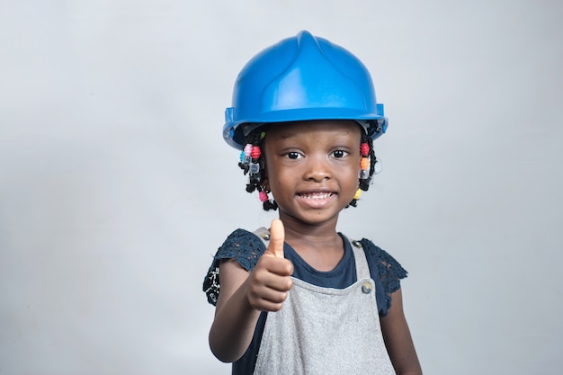 Feliz niña africana vistiendo casco azul y haciendo Thumbs up gesto