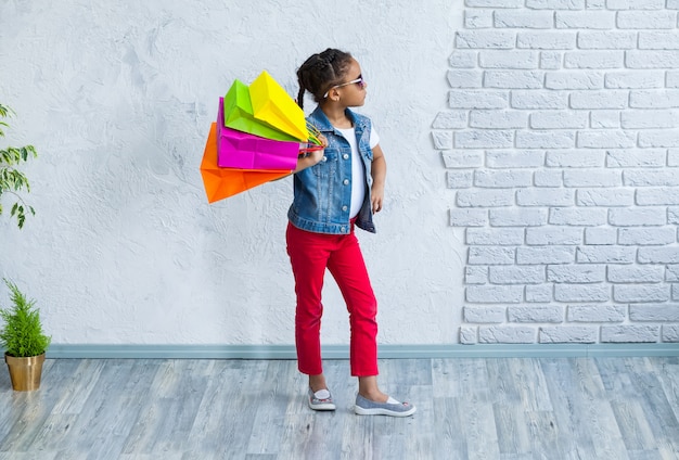 Feliz niña afro con bolsas de compras