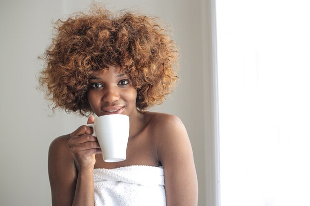 Feliz niña afro con un cafe