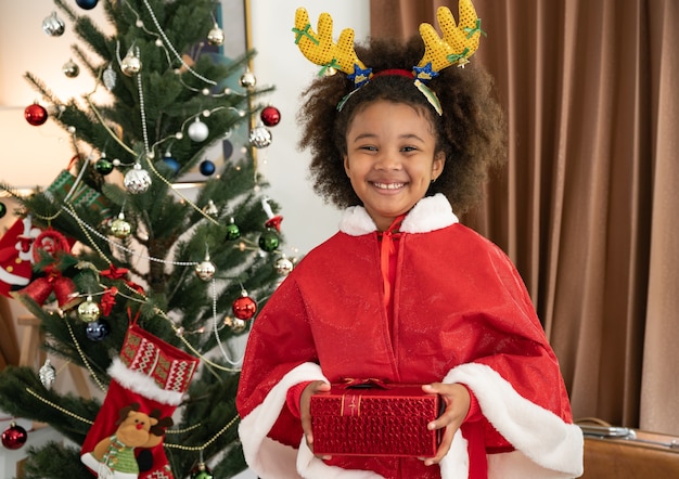 Feliz niña afroamericana niños afro con caja de regalo y adornos navideños