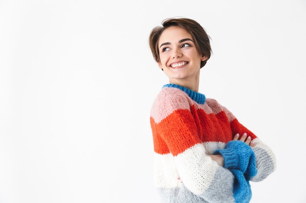 Feliz niña alegre vistiendo suéter que se encuentran aisladas en blanco, posando