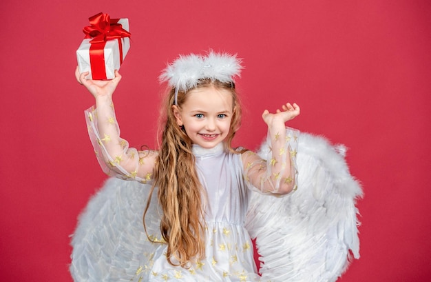 Feliz niña ángel sonriente aislada en rojo juguetón niño angelical de Navidad niños