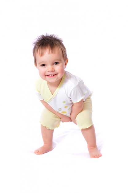 Feliz niña de un año con una camiseta blanca y pantalones cortos amarillos