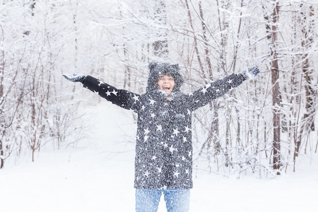 Feliz niña arrojar nieve en un bosque de invierno