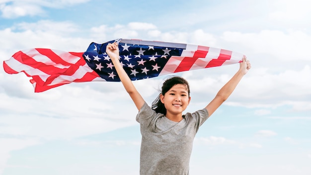 Feliz niña asiática con bandera estadounidense EE. UU. Celebra el 4 de julio