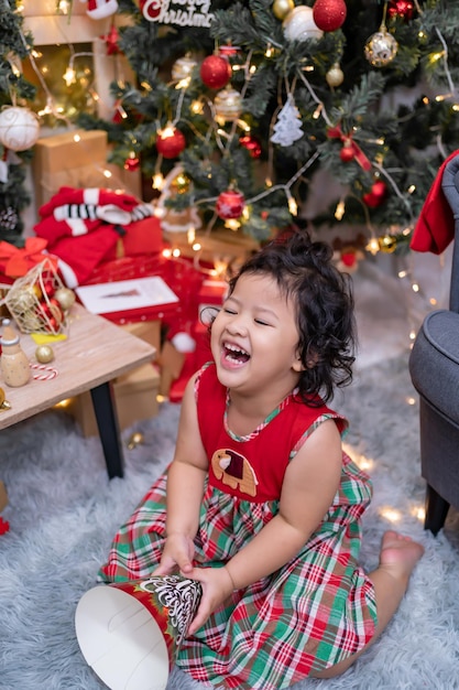 Feliz niña asiática divertirse el día de Navidad. Niño con padre con decoración de árbol de Navidad en casa de vacaciones.