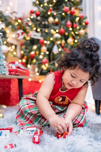 Feliz niña asiática divertirse el día de Navidad. Niño con padre con decoración de árbol de Navidad en casa de vacaciones.