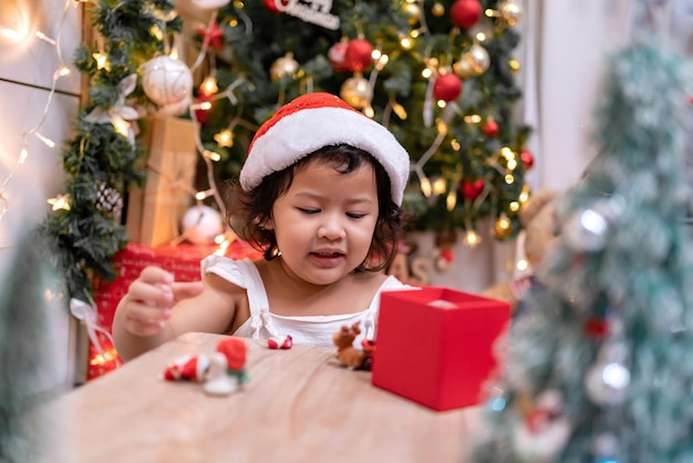 Feliz niña asiática divertirse el día de Navidad. Niño con padre con decoración de árbol de Navidad en casa de vacaciones.