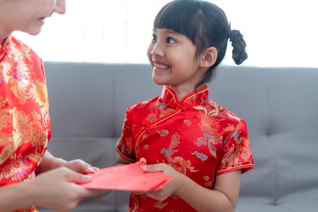 Feliz niña asiática recibió un sobre rojo de la madre para el año nuevo chino