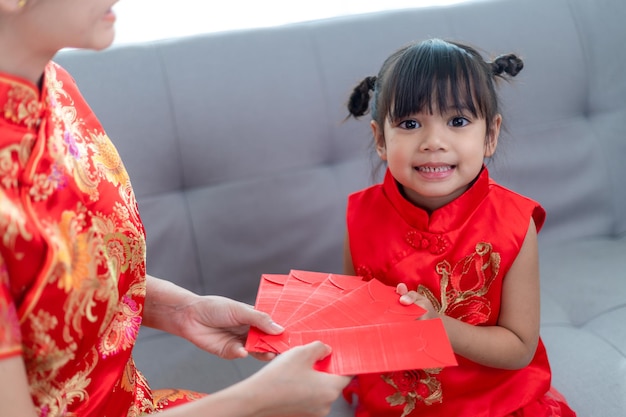 Feliz niña asiática recibió un sobre rojo de la madre para el año nuevo chino