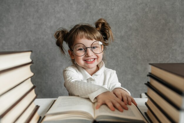 Feliz niña caucásica divertida en vasos leyendo un libro. Chica emocional. Pronto a la escuela.