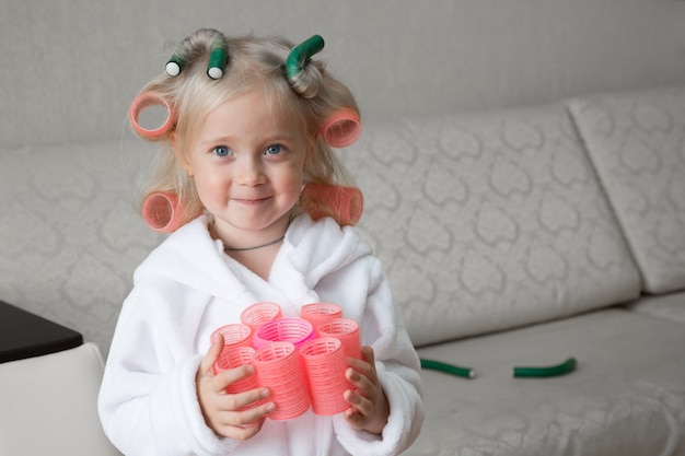 Feliz niña caucásica con rizadores para el cabello.