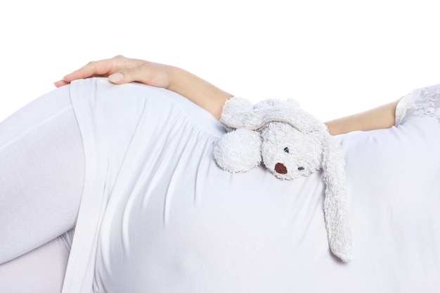 Feliz niña embarazada se encuentra en la pared blanca