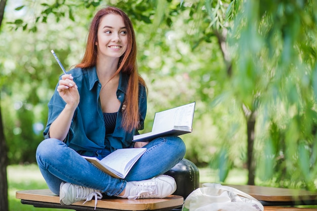 Feliz niña estudiando en el parque