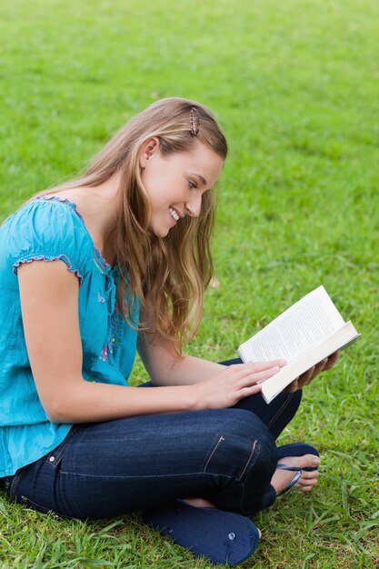 Feliz niña leyendo un libro mientras se está sentado en un parque