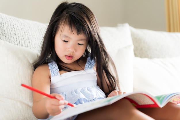 Feliz niña linda sonriendo y sosteniendo lápiz rojo y dibujo