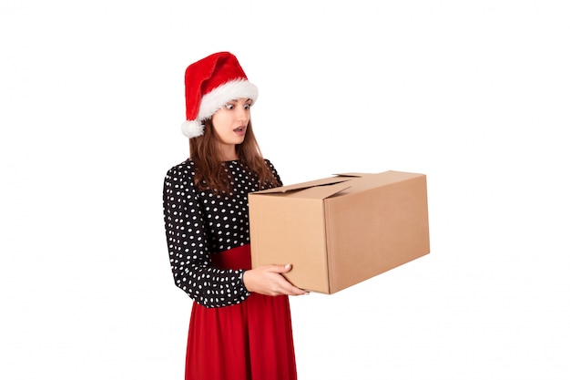 Feliz niña morena en sombrero de Navidad con caja