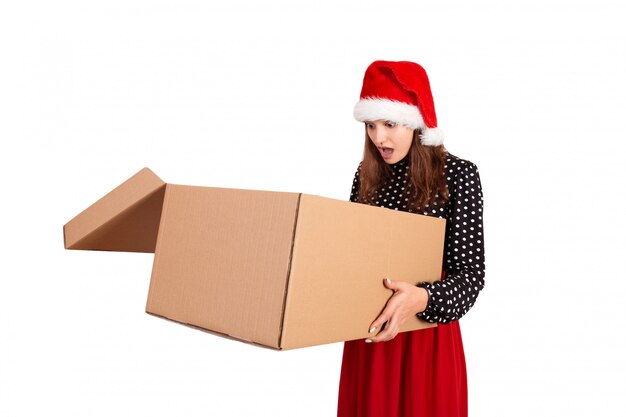 Feliz niña morena en sombrero de Navidad con caja