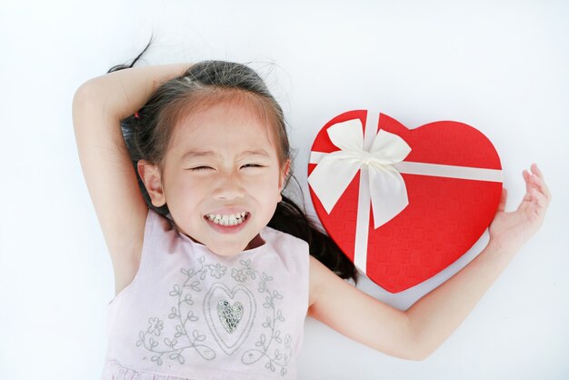 Feliz niña niño con caja de regalo de corazón rojo sobre fondo blanco.