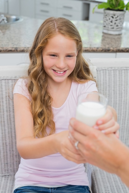 Feliz niña recibe un vaso de leche