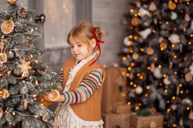 Feliz niña rubia en ropa escandinava, recogiendo mandarinas, preparándose para una fiesta