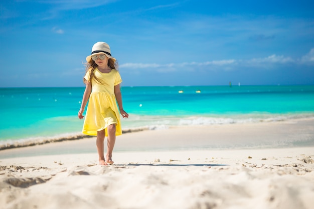 Feliz niña con sombrero en la playa durante las vacaciones de verano