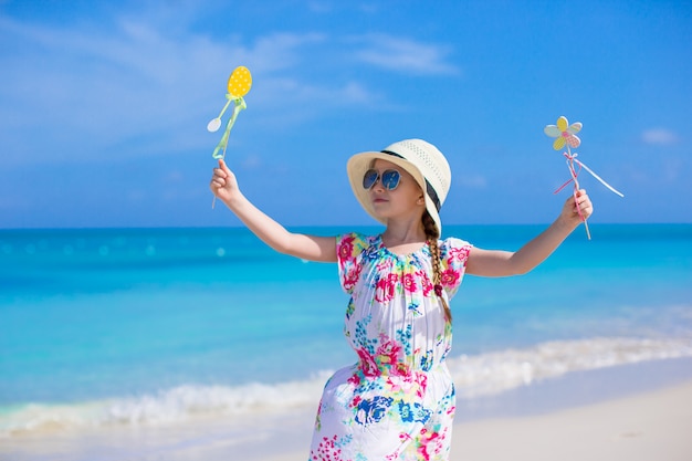 Feliz niña con sombrero en la playa durante las vacaciones de verano