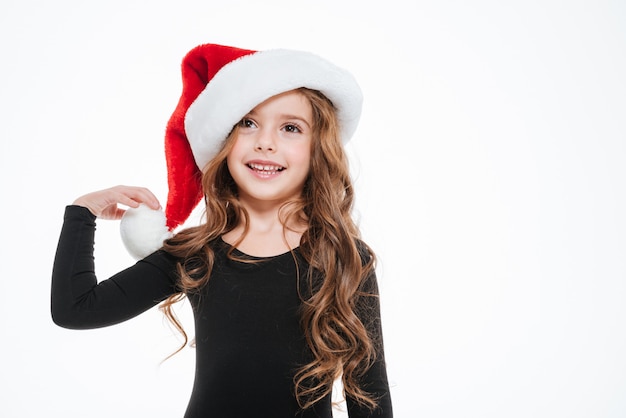 Feliz niña con sombrero de santa claus de pie y sonriente