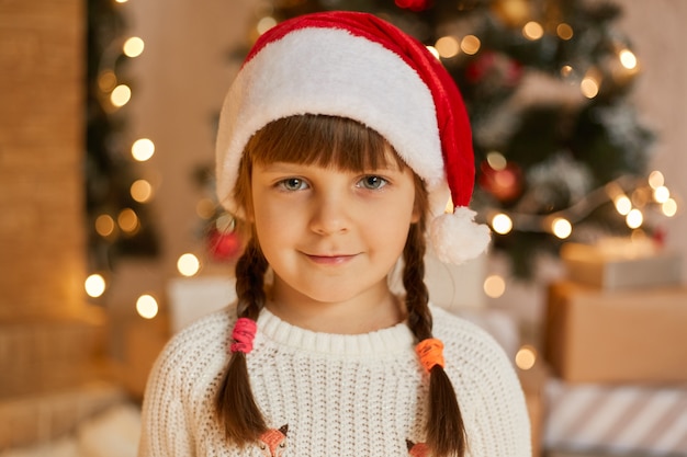 Feliz niña con sombrero de santa tiene humor navideño