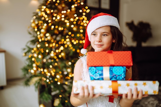 Feliz niña sonriente con cajas de regalo de Navidad. Niño lindo se divierte cerca del árbol.