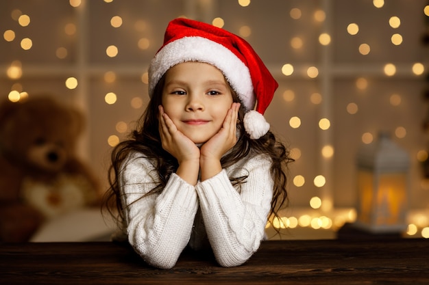 Feliz niña sonriente niño con sombrero de santa soñando con las vacaciones