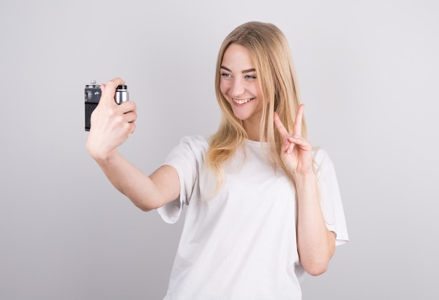 Feliz niña sonriente sosteniendo la cámara y tomando fotografías de sí misma