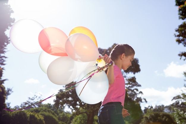 Feliz niña sosteniendo globos