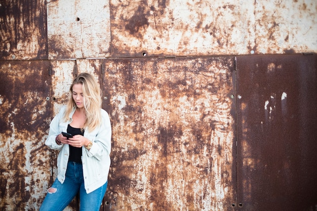 Feliz niña sosteniendo y usando su teléfono inteligente solo - mujer caucásica jugando con su teléfono - millenial 20s - personas