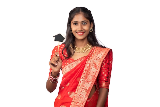 Feliz niña tradicional india sosteniendo una pequeña tabla cortada en sus manos sobre un fondo blanco