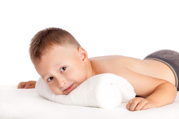 Foto feliz niño acostado en una mesa de masaje esperando masaje