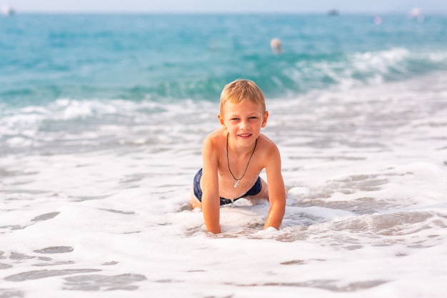 Feliz niño activo divirtiéndose en las olas en la playa