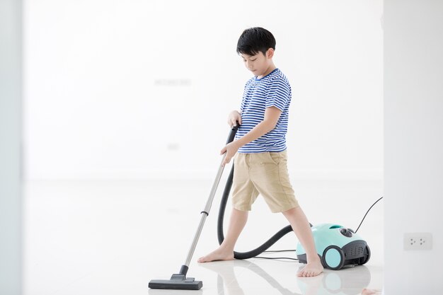 Feliz niño asiático limpiando en la casa