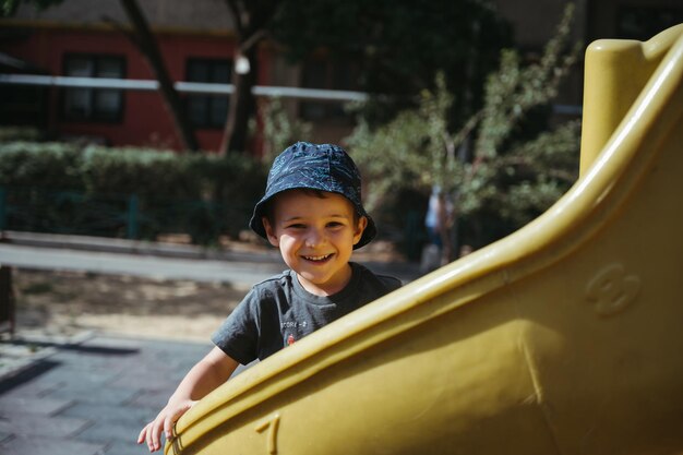 feliz niño de jardín de infantes monta un tobogán en el patio de recreo en verano