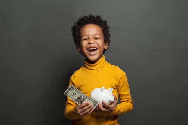 Feliz niño negro con nosotros dólar y caja de dinero