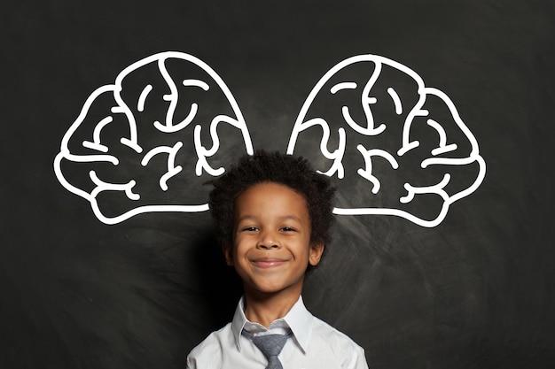 Feliz niño negro sonriente estudiante con gran idea de cerebro y concepto de tormenta de ideas