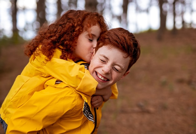 Foto feliz niño y niña pelirroja en impermeables