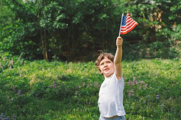 Feliz niño patriótico sosteniendo la bandera estadounidense EE.UU. celebra el 4 de julio Feliz día de la independencia