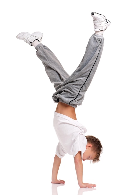 Feliz niño pequeño gimnasia acrobacias postura de equilibrio aislado en fondo blanco