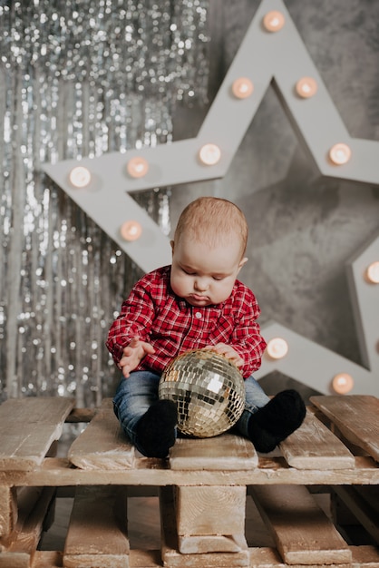 Feliz niño recién nacido sentado en el fondo de la decoración de Navidad