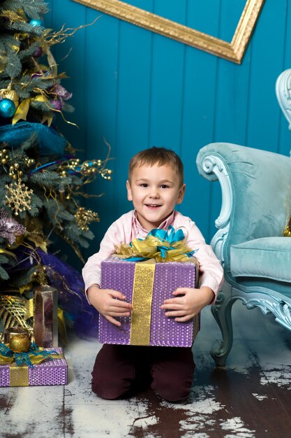 Feliz niño sonriente tiene caja de regalo de Navidad.