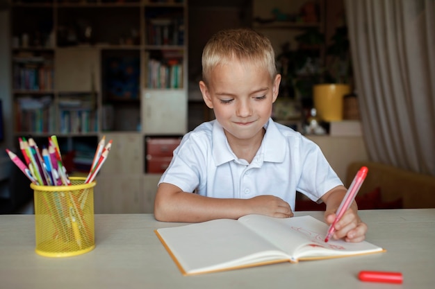 Feliz niño zurdo escribiendo en el libro de papel con su mano izquierda día internacional del zurdo