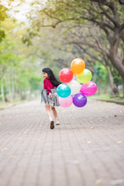 Feliz niños niña paño rojo sonrisa y corriendo con globos de colores